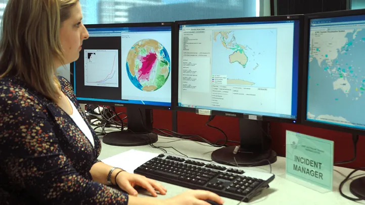 Joint Australian Tsunami Warning Centre expert looking at tsunami radars on three computer screens.