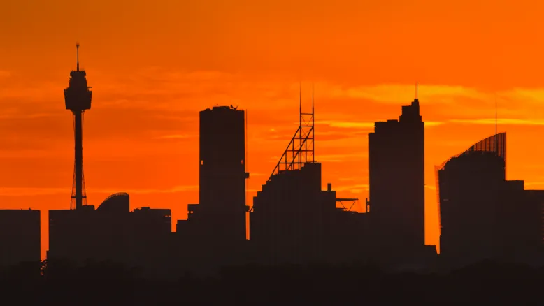 Photo of dark city skyline against an orange sky representing heatwave conditions.