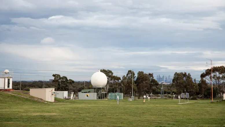 Doppler radar in a green grassy environment under a pale overcast sky.