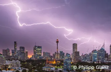Lightning bolt arcing through a purple and white sky above the Sydney skyline.