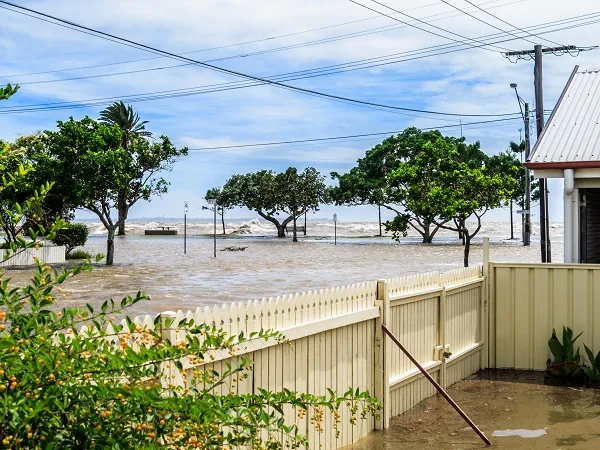 Flood water rises against a fence and covers the ground as sea water floods onto the land.