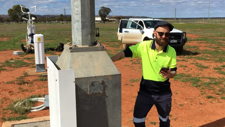 Nathan Turner in hi-vis work clothes, checking observing equipment in the field.